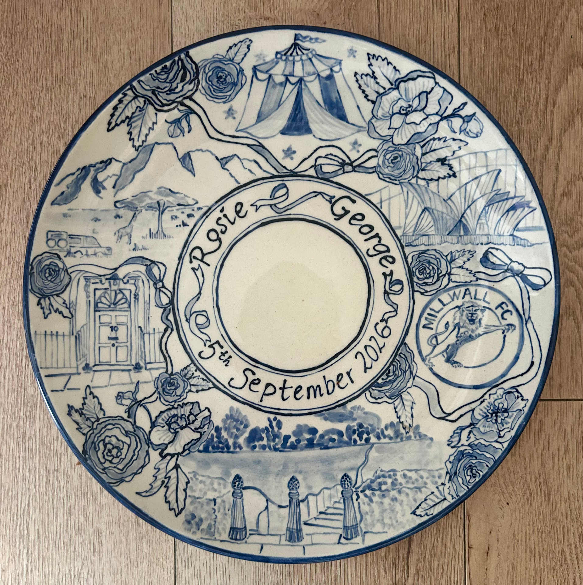 Hand-painted blue and white celebration plate for Rosie and George with circus tent, Sydney Opera House, Millwall FC crest and 10 Downing Street