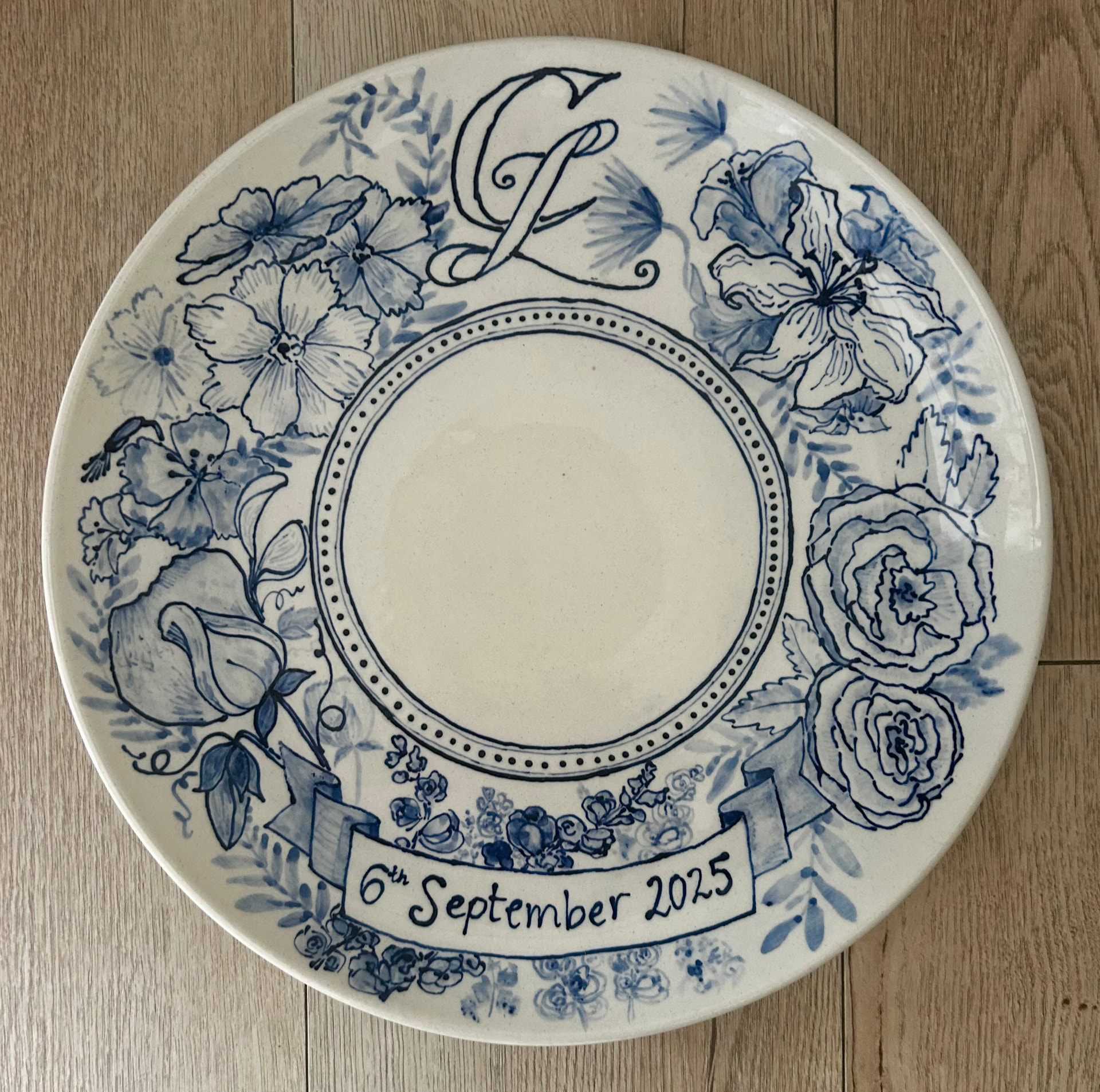 Hand-painted blue and white celebration plate for Lucy and Charlie with CL monogram and floral border